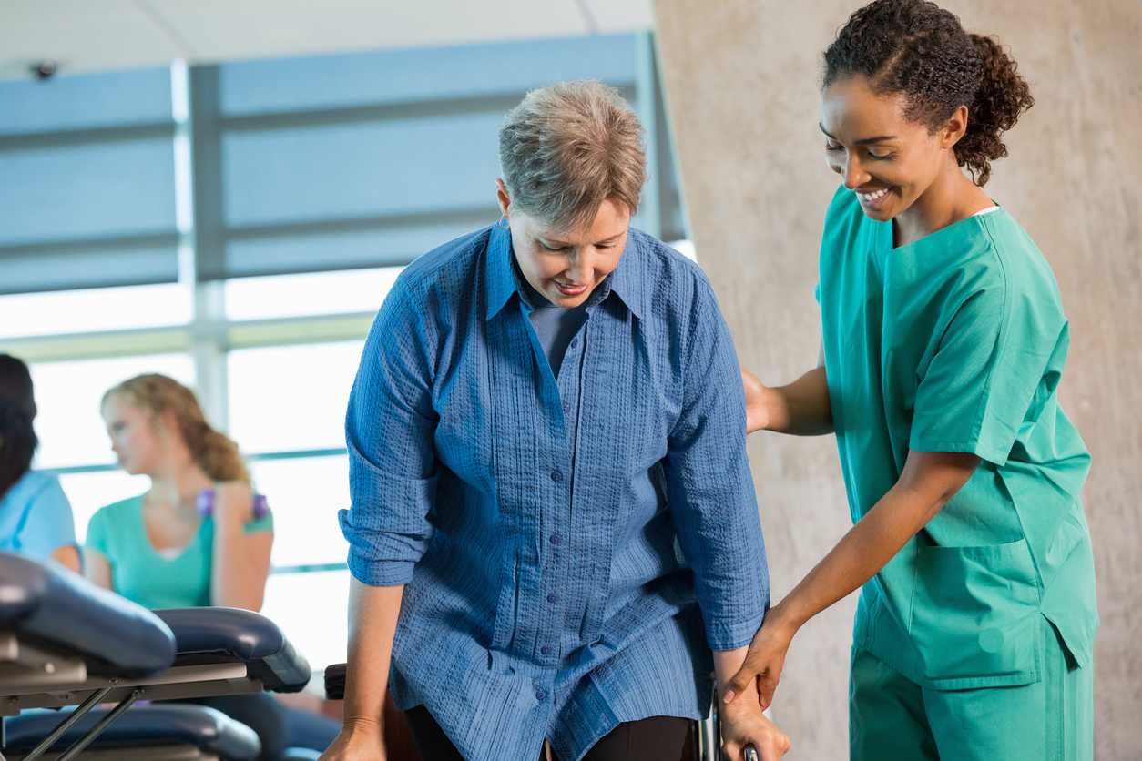 Nurse or physical therapist assisting senior patient in wheelchair falls prevention